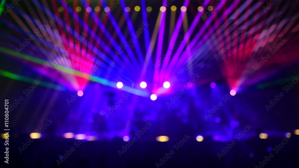 Unrecognizable people watching a beautiful laser show with multicolored lights
