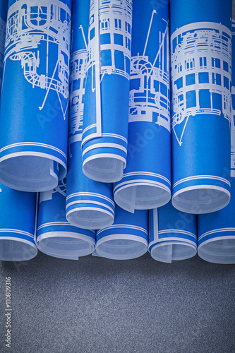 Set of blue rolled engineering drawings on grey background const
