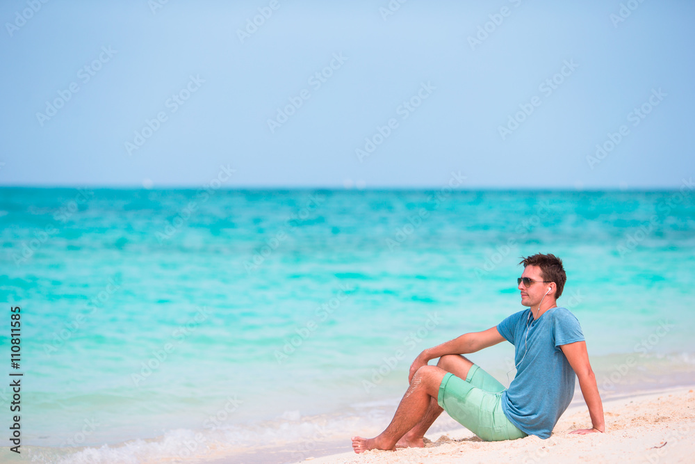 Young man enjoying the music on white beach