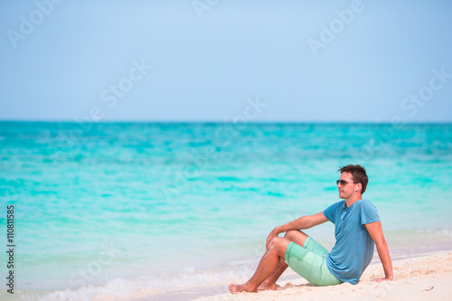 Young man enjoying the music on white beach