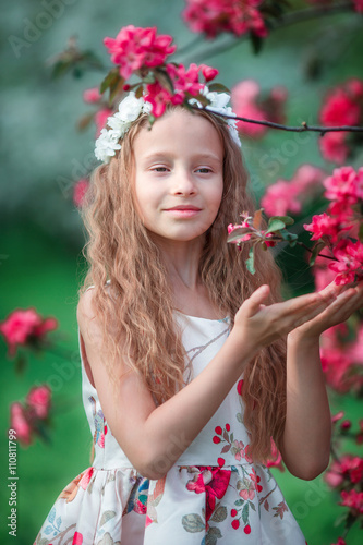 Adorable little girl in blooming spring apple garden outdoors