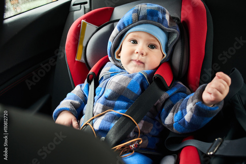 Portrait one year old baby in child's car seat in street clothes