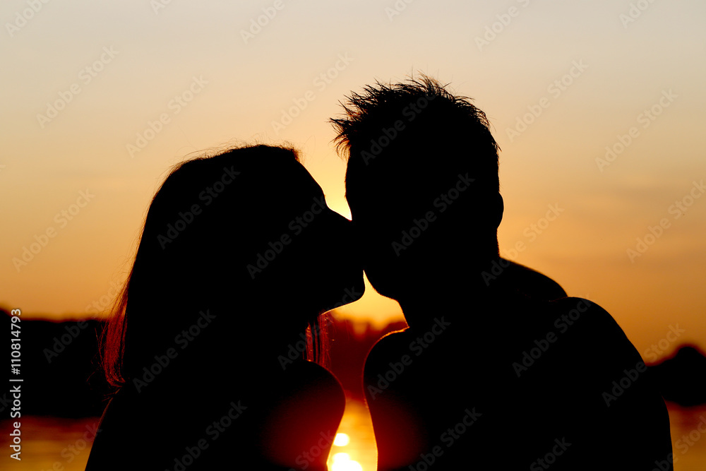 girl kissing a boy at sunset