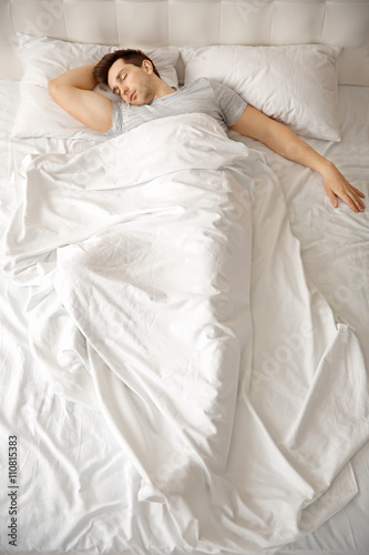 Young man sleeping alone in...