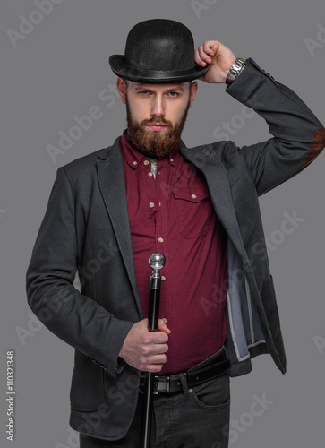 Tattooed bearded man in a suit holding cane