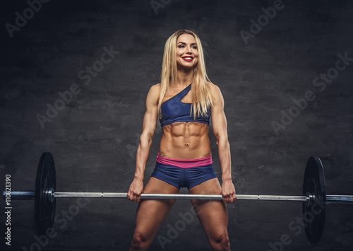 Blond sporty female with barbell.