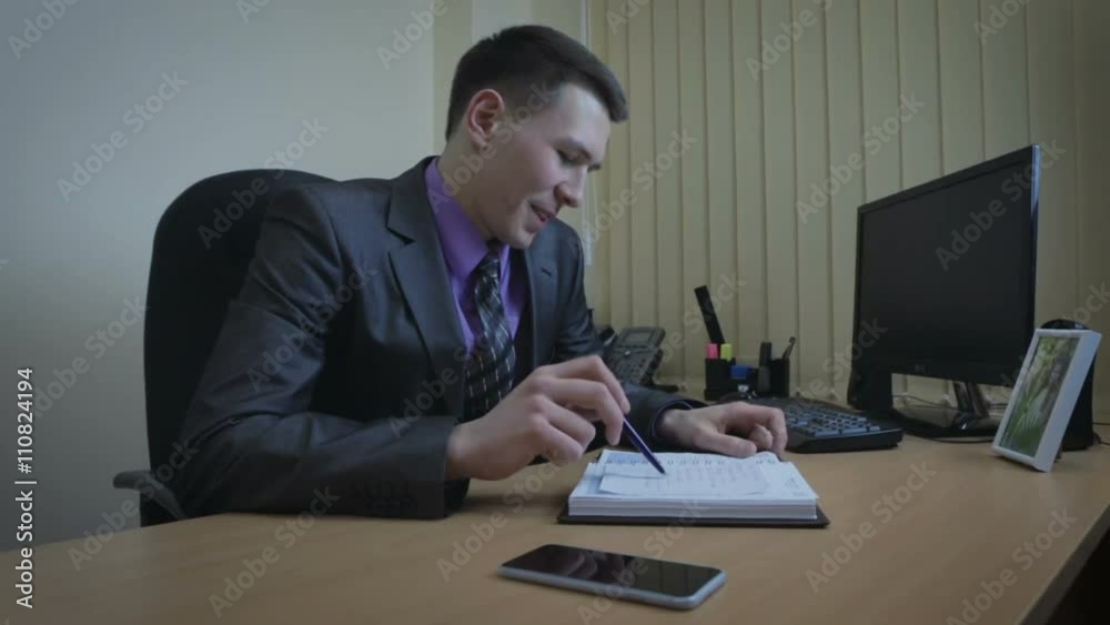 Businessman finishes work. He looks at the picture and leaves office.