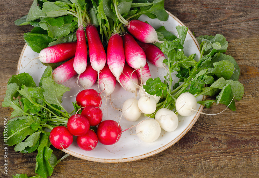 Bundle of fresh organic radishes with leaves on a rustic table. Bundle of fresh organic radishes with leaves on a rustic table.