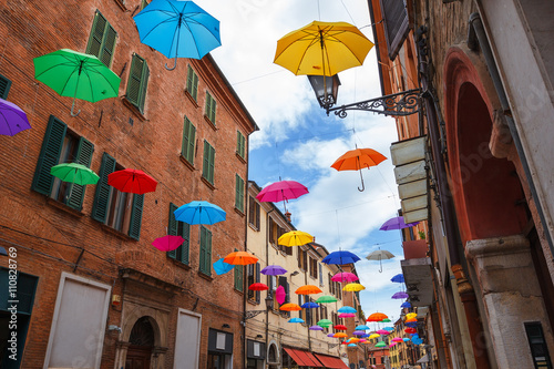 Colorful umbrellas hanging above street of Ferrara, Italy photo