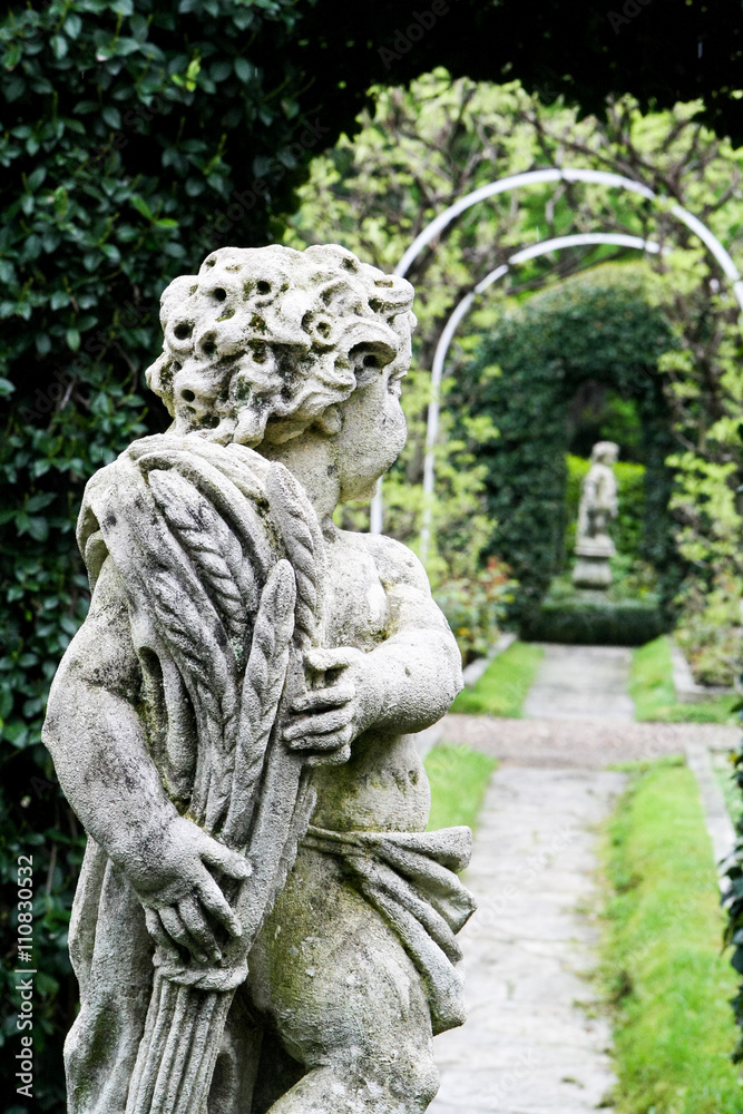 Statue of the boy in the garden. In the background is another statue