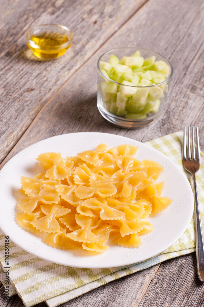 Farfalle on a white plate on wooden background, top view Farfalle on a white plate on wooden background, top view