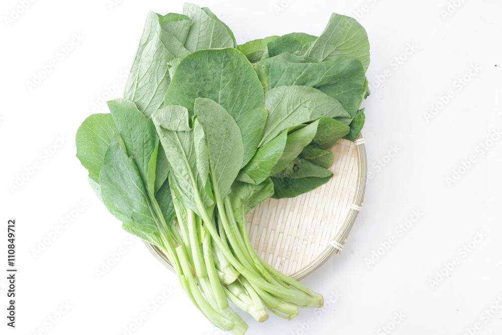 Fresh green mustard in wicker tray on isolated white background. Fresh green mustard in wicker tray on isolated white background.