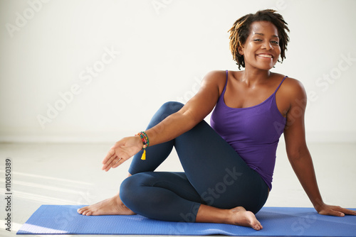 Cheerful African-American woman practicing asana in yoga class