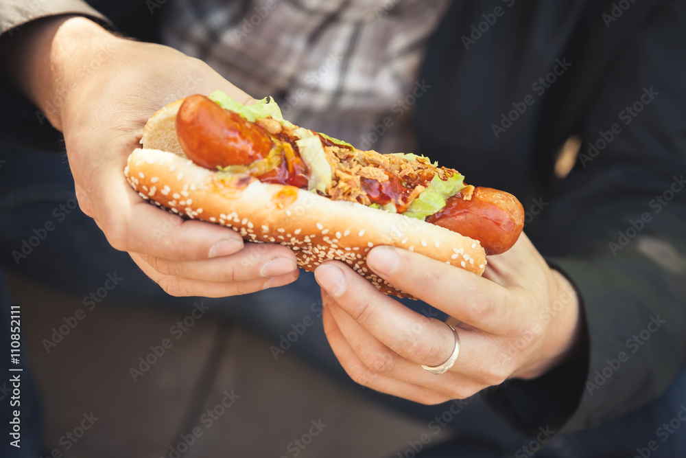Man holds fresh hot dog in hands, closeup