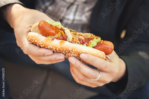Man holds fresh hot dog in hands, closeup © evannovostro