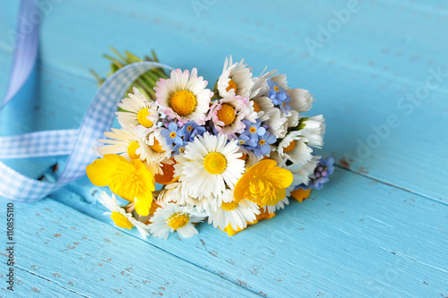 Blumenstrauß mit selbst gepflückten Blumen, Gänseblümchen, Sumpfdotterblume, Vergissmeinnicht  auf blauem Holz
