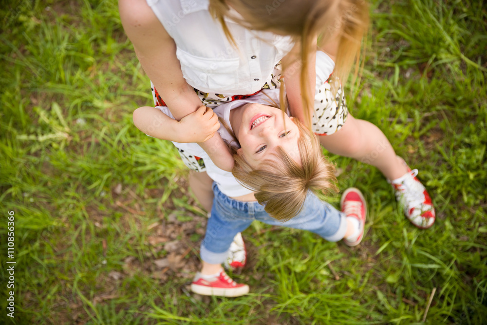 Top view on adorable blond kid boy hugging his young mother in the park. Outdoors. Happy family walking in the park on a summer sunny day. Top view on adorable blond kid boy hugging his young mother in the park. Outdoors. Happy family walking in the park on a summer sunny day.