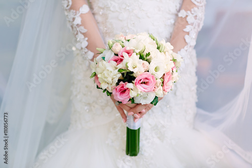    Beautiful wedding bouquet of flowers in hands of the bride.