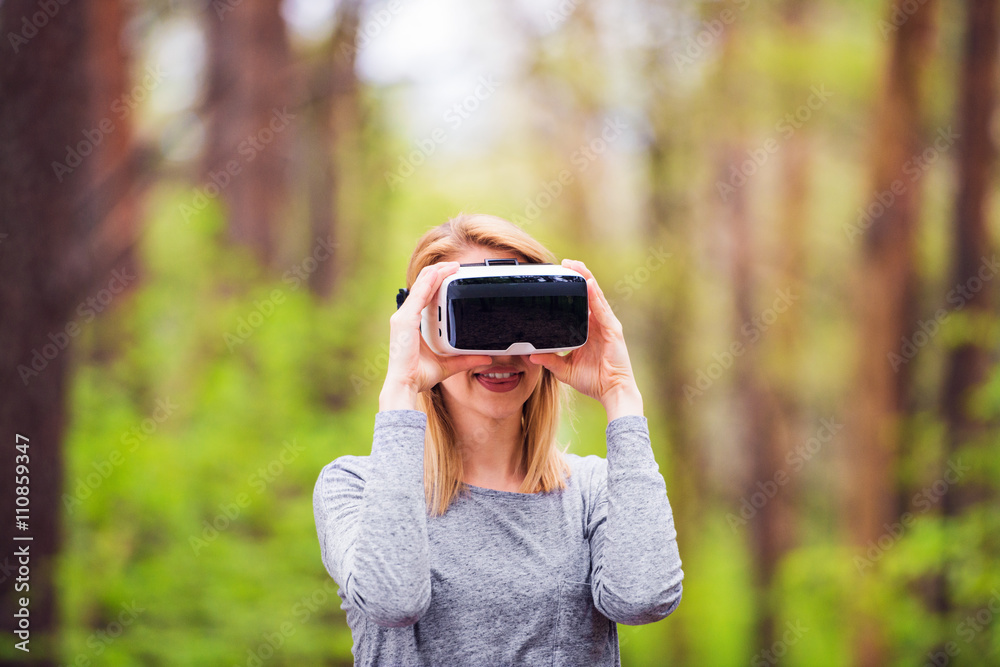 Woman wearing virtual reality goggles outside in spring nature