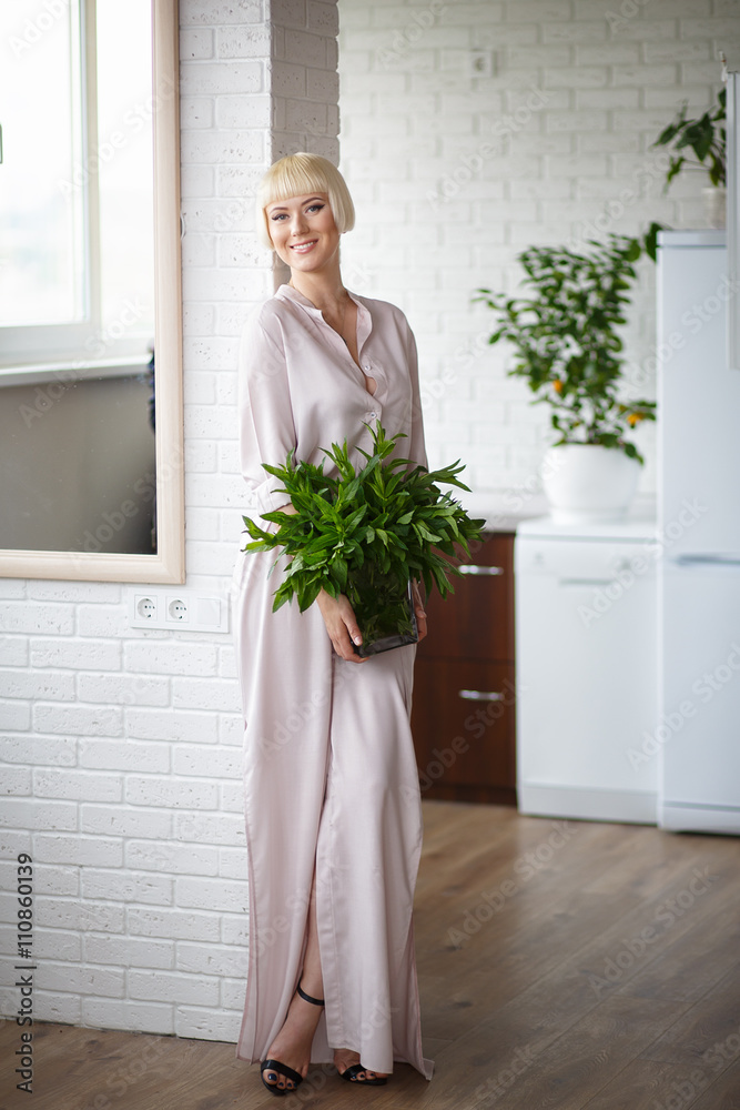 woman in a beige dress with a bouquet of mint in hand, standing woman in a beige dress with a bouquet of mint in hand, standing