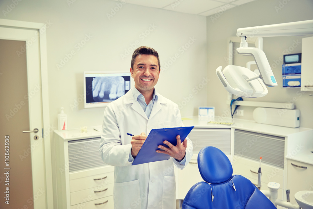 happy male dentist with clipboard at dental clinic happy male dentist with clipboard at dental clinic