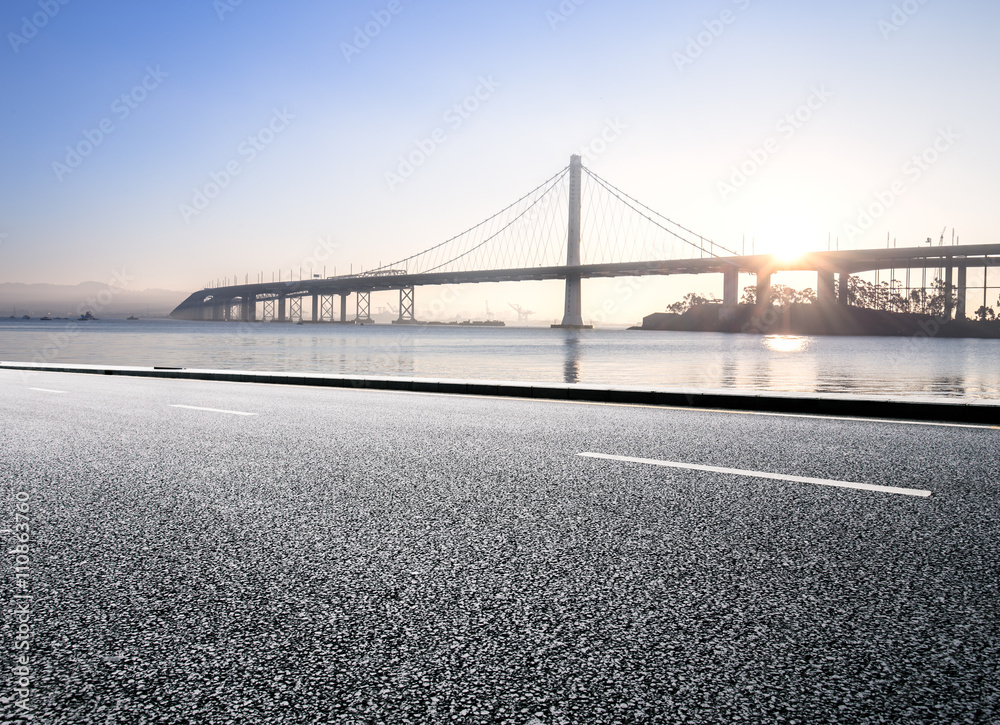 empty asphalt road with tranquil water and gold gate bridge at s