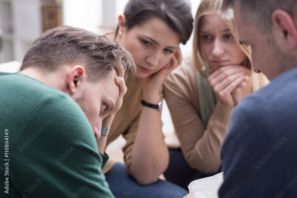 People comforting young man during group therapy session People comforting young man during group therapy session