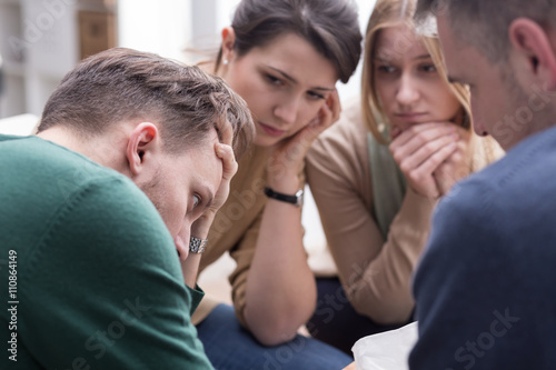 People comforting young man during group therapy session