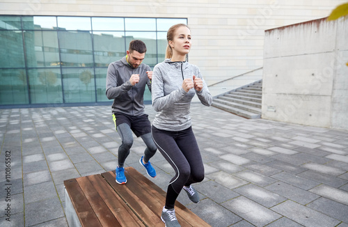 couple making step exercise on city street bench