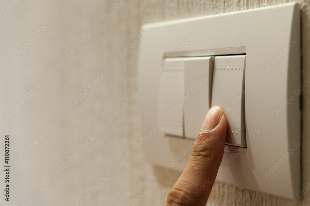 Closeup of A finger is turning on a lighting switch on wallpaper ...