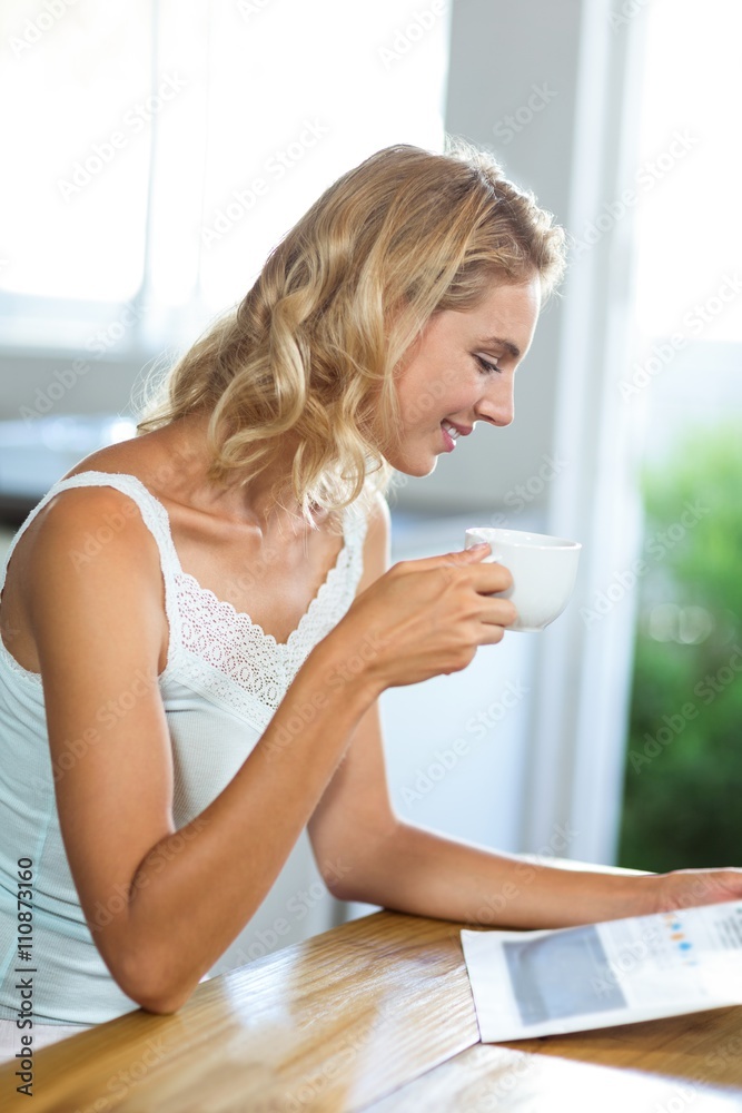 Smiling woman reading newspaper