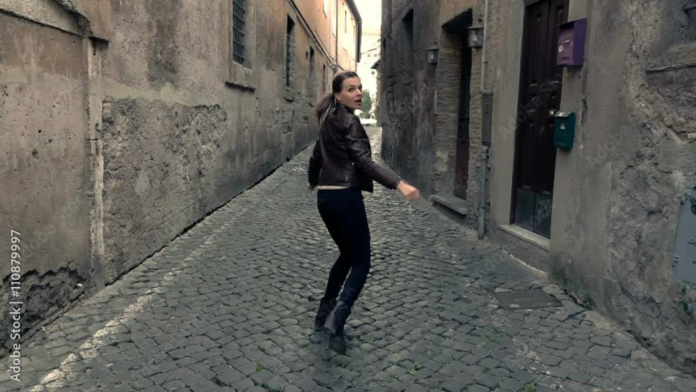 Afraid, scared woman running through street in the city,  super slow motion 
