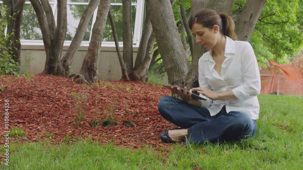 caucasian woman sitting in the grass park with tablet caucasian woman sitting in the grass park with tablet