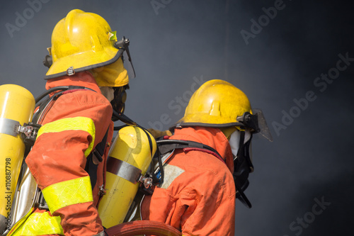 2 firefighters in operation and dark smoke background