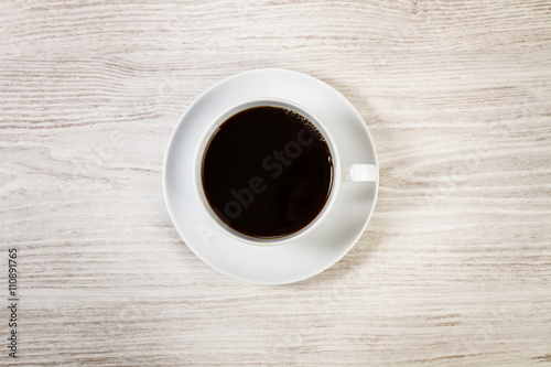 Taza de café vista desde arriba sobre tabla de madera blanca. Copy space