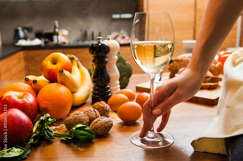 Young woman hand holding glass of wine in kitchen Young woman hand holding glass of wine in kitchen