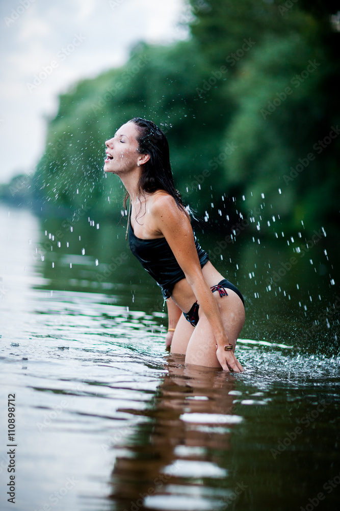 Fototapeta premium A woman flipping her wet hair making a rainbow of water with her hair.
