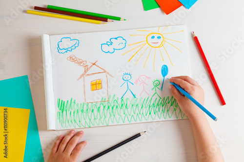 Child draws a pencil drawing of the house and his family.