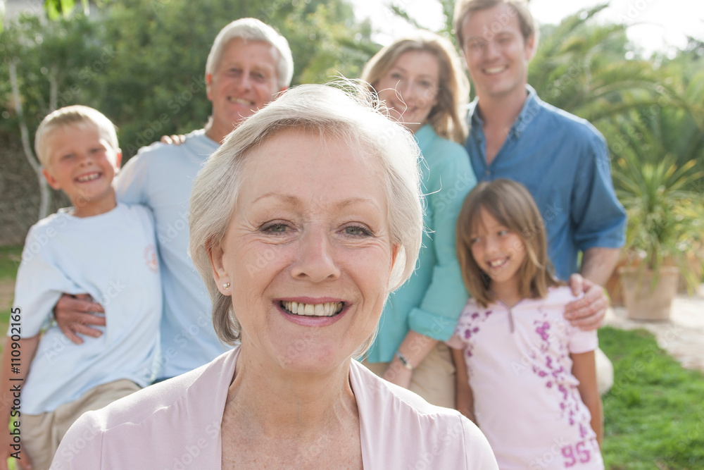 Portrait of senior woman in front of family looking at camera smiling Portrait of senior woman in front of family looking at camera smiling