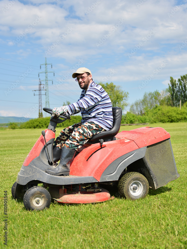 Fototapeta premium Smiling handicapped boy on lawn mower