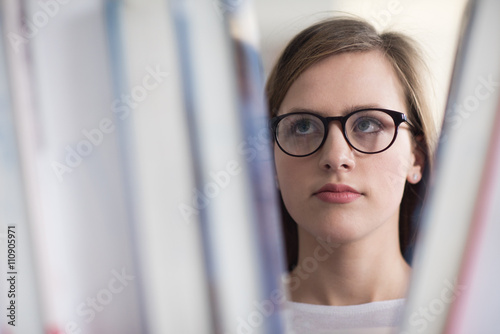 portrait of famale student selecting book to read in library