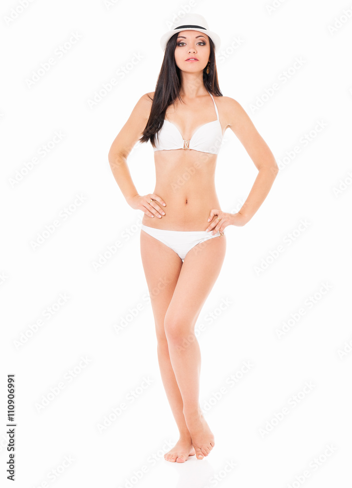 Sexy young brunette woman posing in a white bikini and hat, isolated on white background Sexy young brunette woman posing in a white bikini and hat, isolated on white background