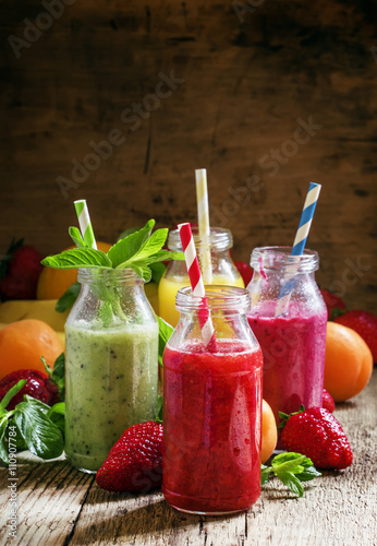 Multi-colored bottles with fresh fruit smoothies with striped st