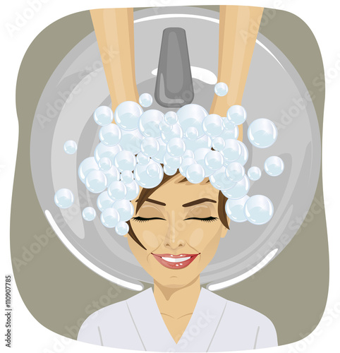 young woman with hairdresser washing head at hair salon
