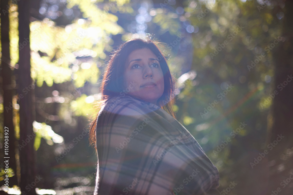 Woman wrapped in checkered shawl in forest Woman wrapped in checkered shawl in forest