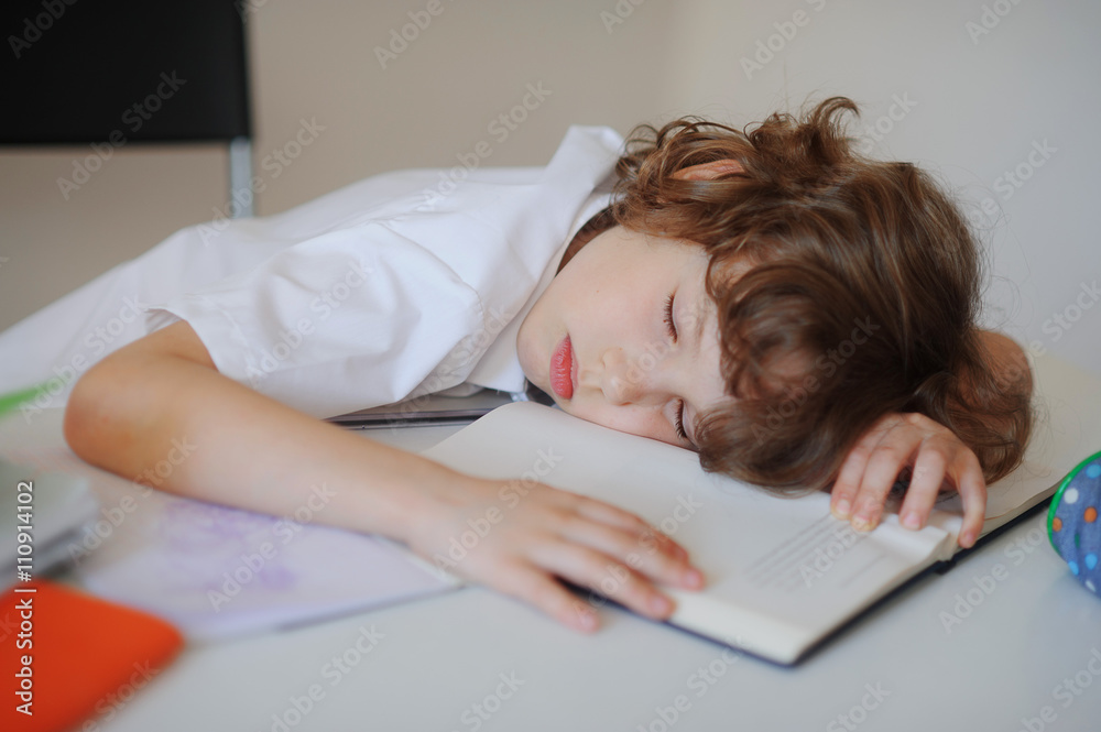 The boy fell asleep in the classroom sitting at a school desk The boy fell asleep in the classroom sitting at a school desk