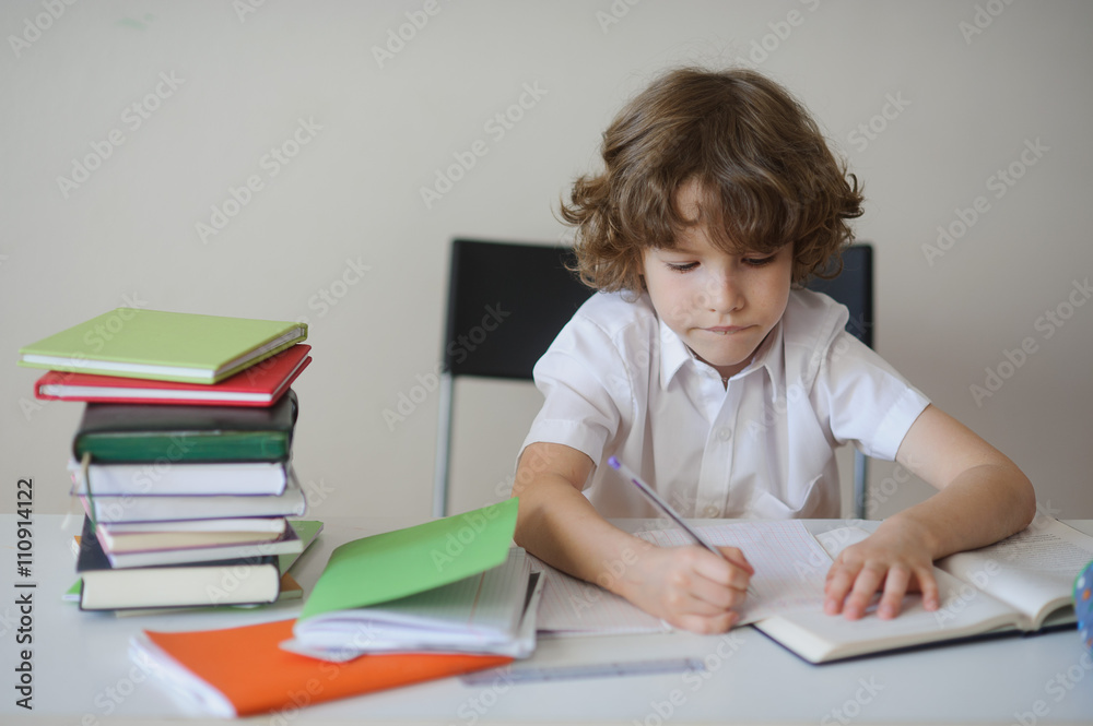 Boy diligently does his homework sitting at a school desk Boy diligently does his homework sitting at a school desk