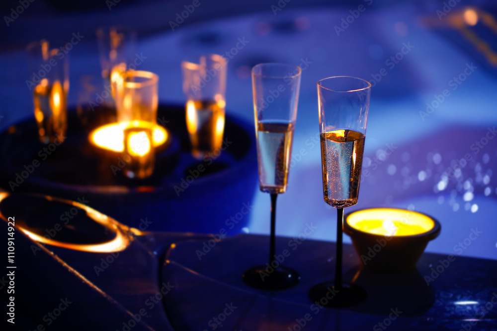 Candlelit champagne glasses beside a jacuzzi