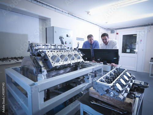 Engineers inspecting automotive engine in test facility photo