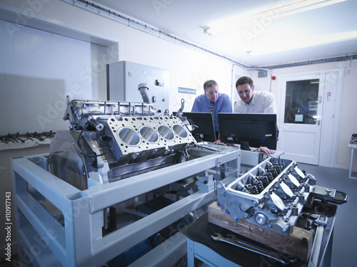 Engineers inspecting automotive engine in test facility